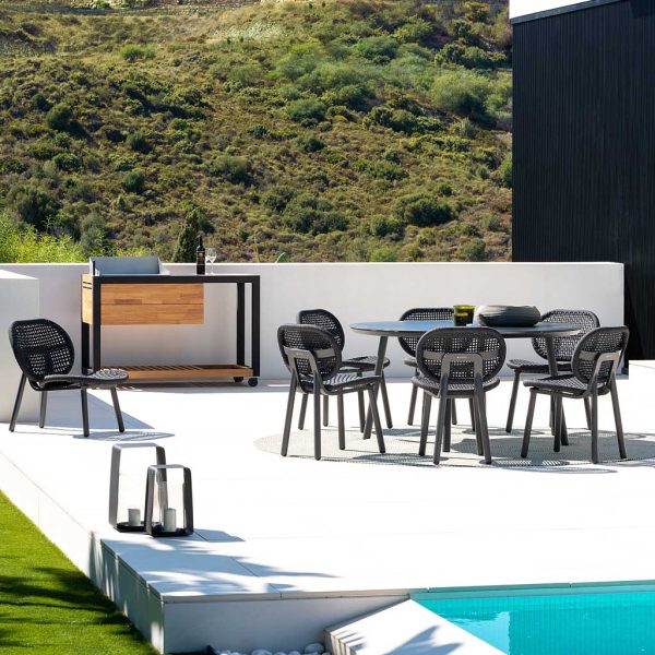 Image of Durham modern circular outdoor table and Skate dining chairs on sunny poolside terrace