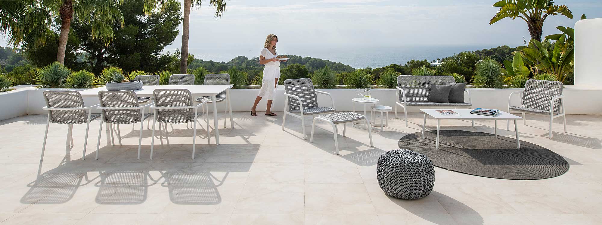 Image of woman stood holding a bowl of fruit in amongst Durham contemporary outdoor furniture, shown in sunny terrace
