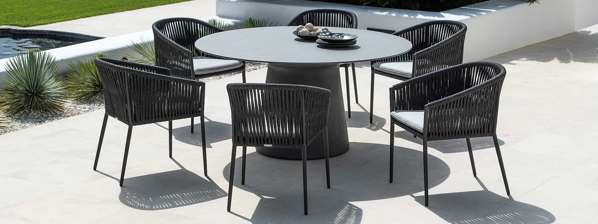Image of Jati & Kebon Fortuna Rope charcoal black garden dining chairs around a chic circular garden table on a sunny terrace