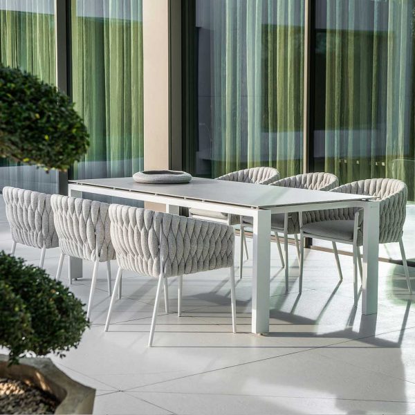 Image of light grey Fortuna Socks garden tub chairs around a rectangular garden table on terrace, with floor to ceiling glass in the background