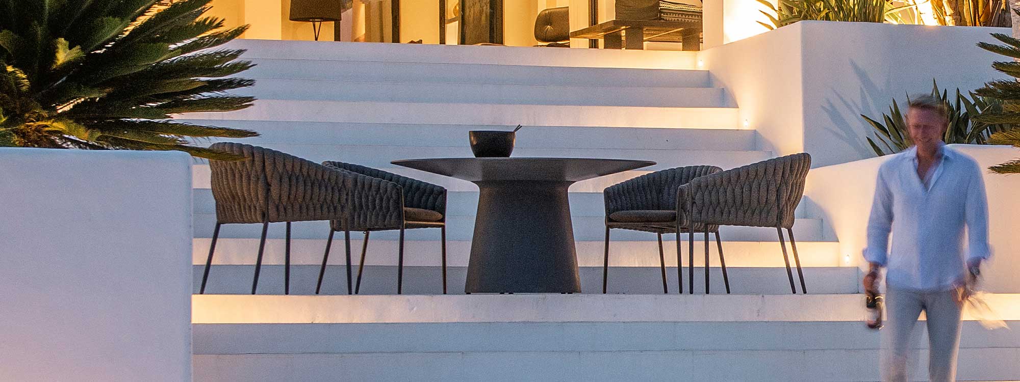 Image of illuminated white-washed terrace with Fortuna Socks black garden tub chairs by Jati & Kebon
