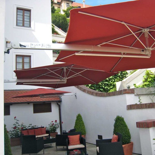 Image of Prostor P4 terracotta coloured wall mounted parasols in hotel courtyard above bistro furniture