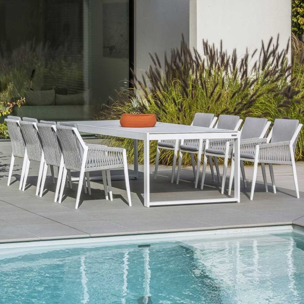 Image of 8 Ritz white garden chairs and Vigo XL rectangular garden table on poolside with architectural grasses in the background