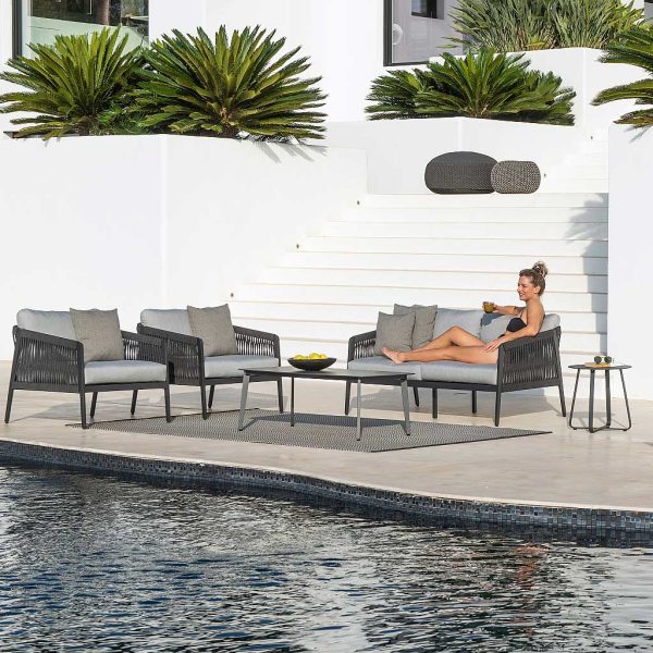 Image of woman relaxing on Ritz Aluminium contemporary garden lounge furniture by Jati & Kebon on sunny poolside with exotic plants and whitewashed wall in the background