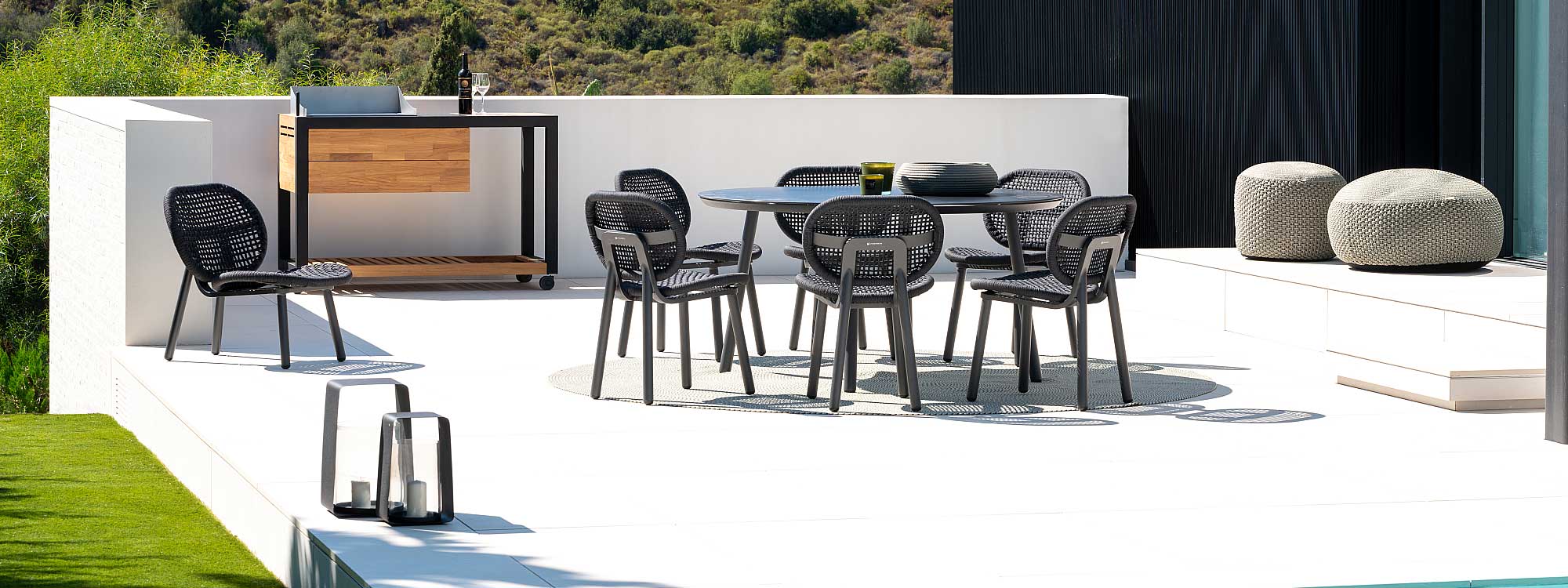 Image of Skate black garden dining chairs around Durham circular table by Jati & Kebon, shown on white-washed poolside