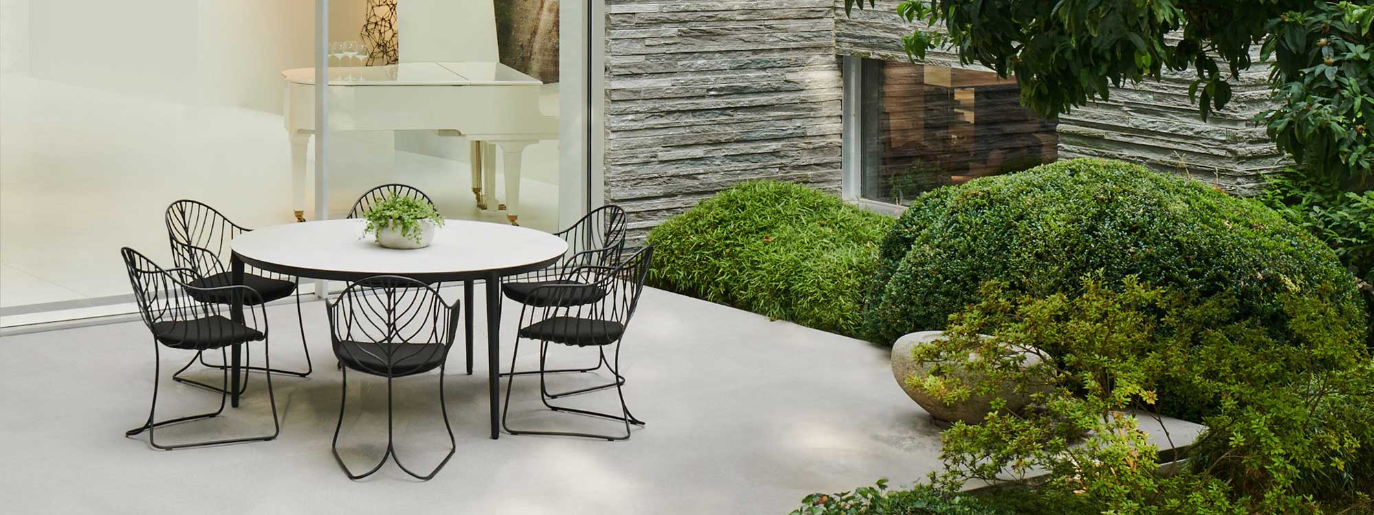 Image of Folia chairs around a circular U-nite garden table by Royal Botania, with white grand piano in the background