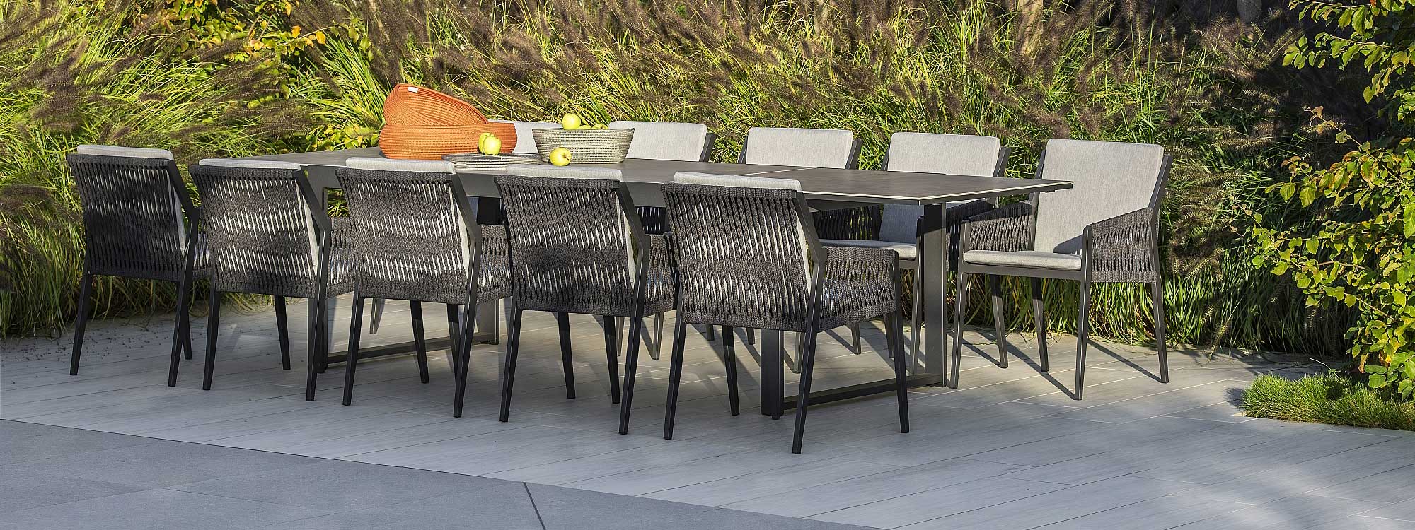 Image of Vigo XL black extending garden table with dark marble ceramic top, shown with 10 Ritz contemporary garden chairs by Jati & Kebon