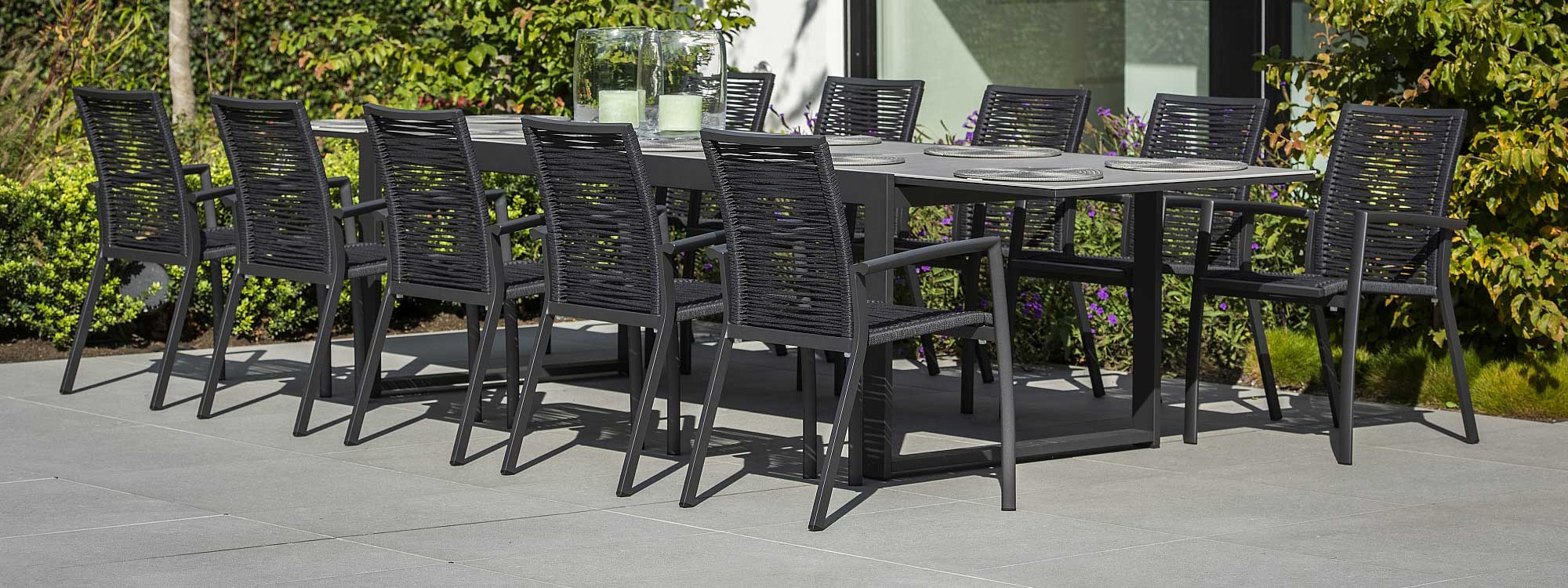 Image of black Vigo XL extending garden table with cement grey ceramic table top, together with 10 Sevilla garden chairs by Jati & Kebon