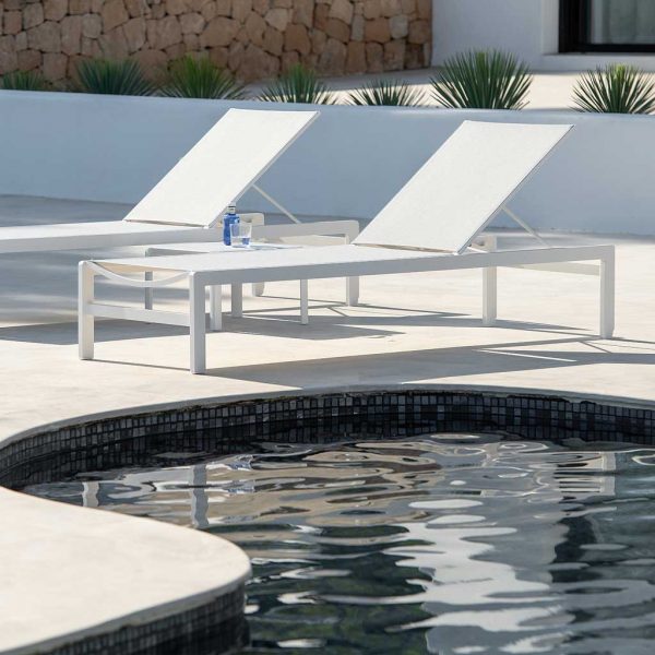 Image of Sylt modern aluminium sun loungers in white on poolside, with whitewashed wall and tropical plants in background