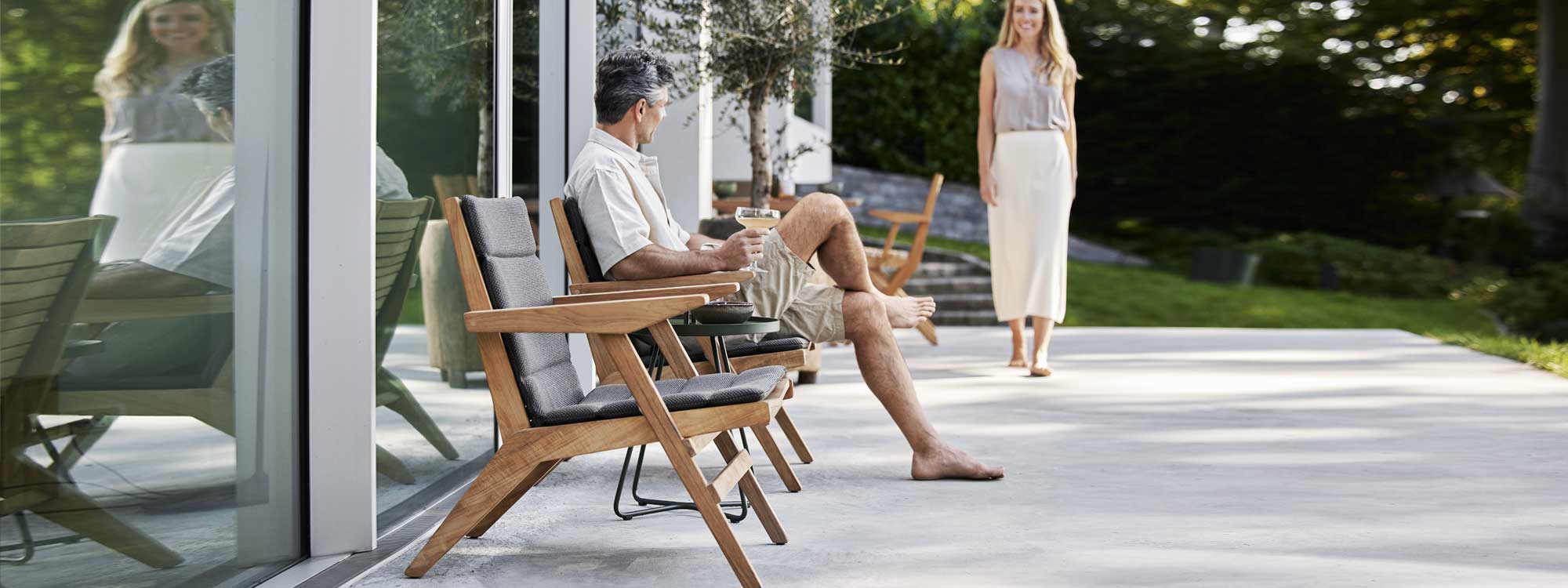 Image of man on terrace sat on Flip adjustable teak lounge chair with light-grey Focus fabric cushion by Cane-line