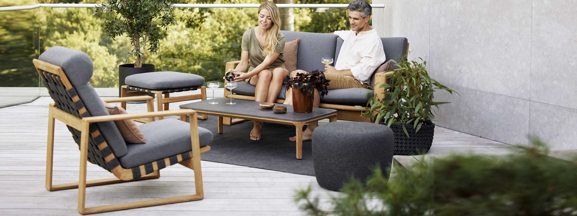 Image of couple sat on Endless Soft 2 seat teak sofa next to Aspect ceramic low table by Caneline