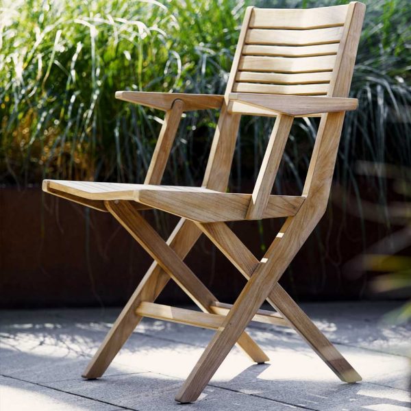 Image of Cane-line Flip folding teak armchair with grasses in background