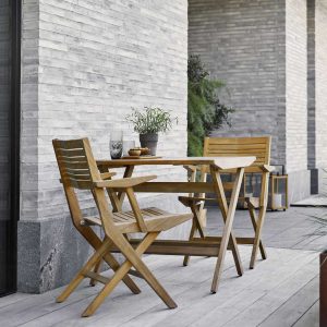 Image of pair of Cane-line Flip folding teak armchairs and small folding teak table on minimalist terrace
