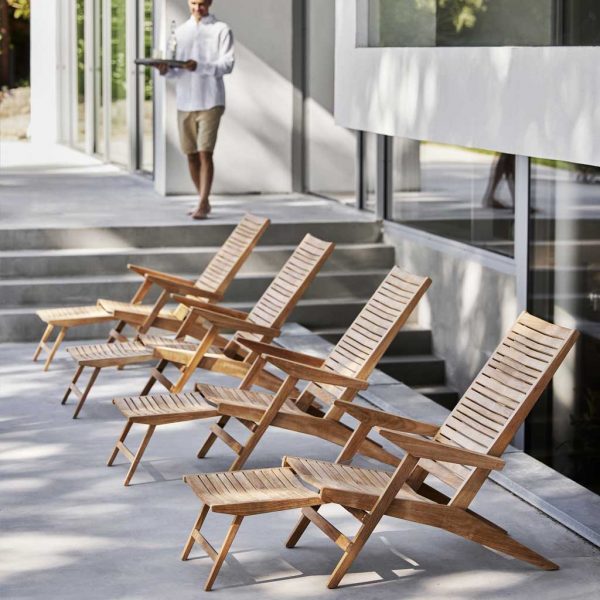 Image of row of 4 Flip teak reclining chairs with foot rests extended by Cane-line