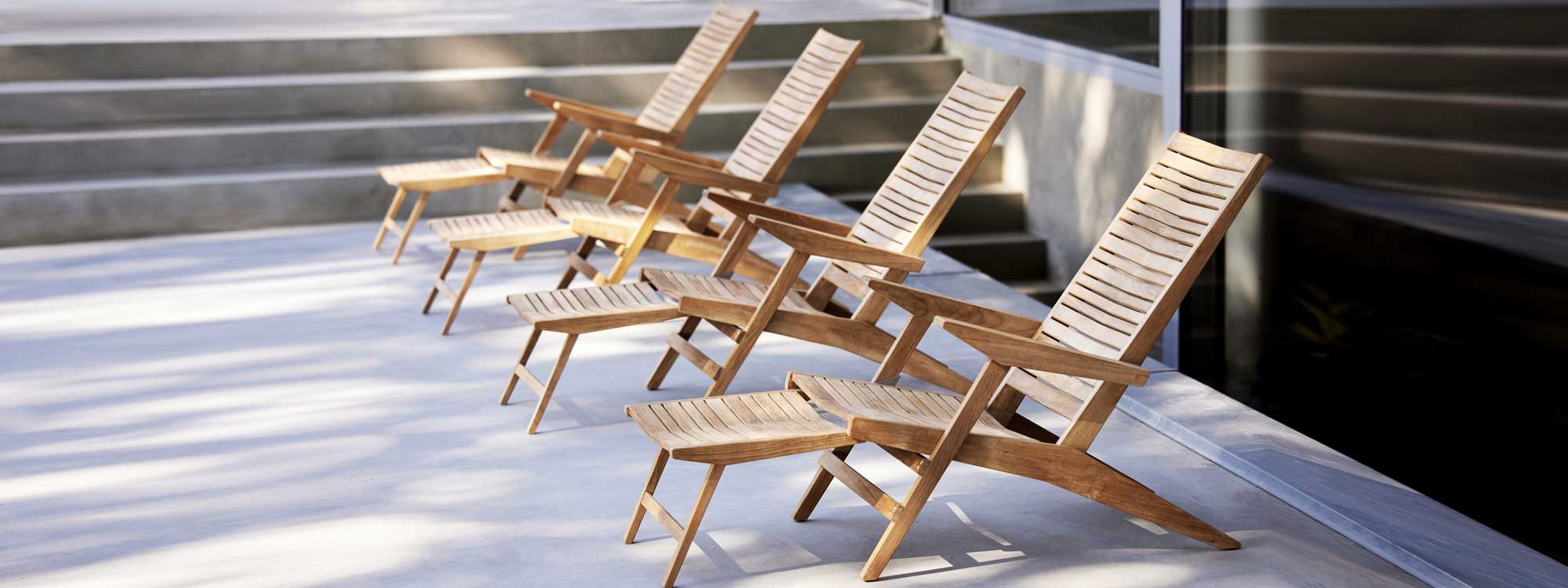 Image of row of Flip modern teak recliners with integrated foot rests designed by Strand+Hvass for Cane-line
