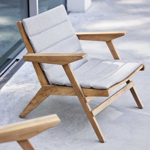 Image of Cane-line Flip adjustable teak lounge chair with grey cushion, shown on concrete terrace