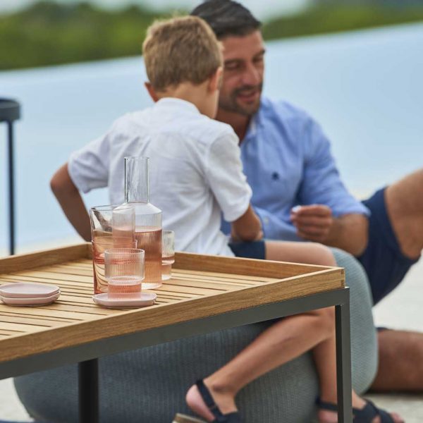 Image of Cane-line Level coffee table with Lava-grey frame and teak top, with father and son in background
