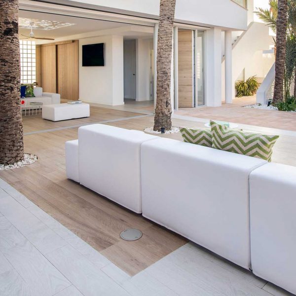 Image of Elements white modular garden sofa on modern whitewashed terrace, with palm trees in the background