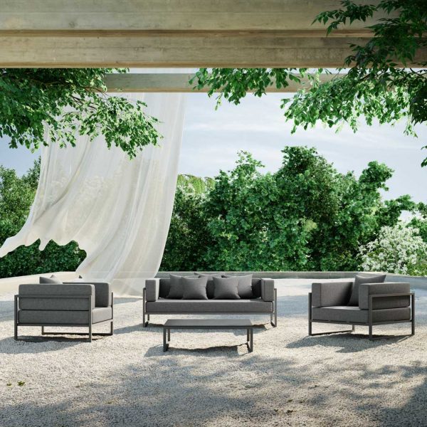 Image of Oiside Línea architectural garden sofa and lounge chairs on gravel terrace with trees on the background