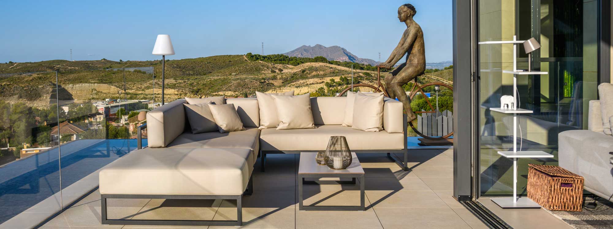 Image of Oiside Línea L shaped outdoor sofa and low table on terrace with scorched hills in the background