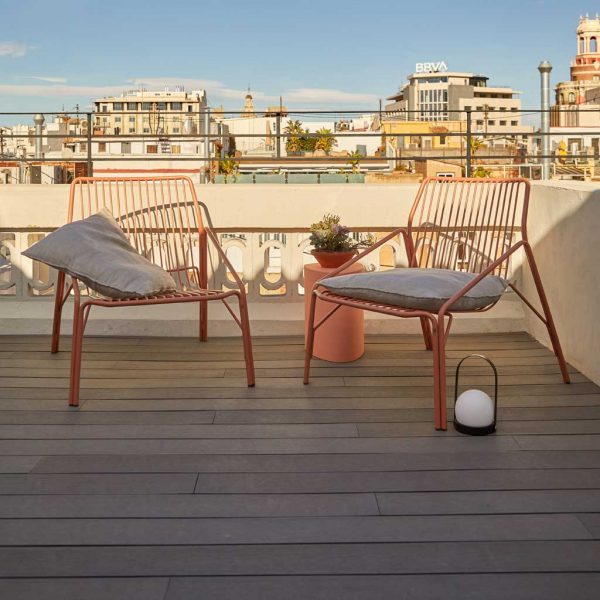 Image of pair of No 12 orange garden lounge chairs on city rooftop terrace with roofs and buildings in the background