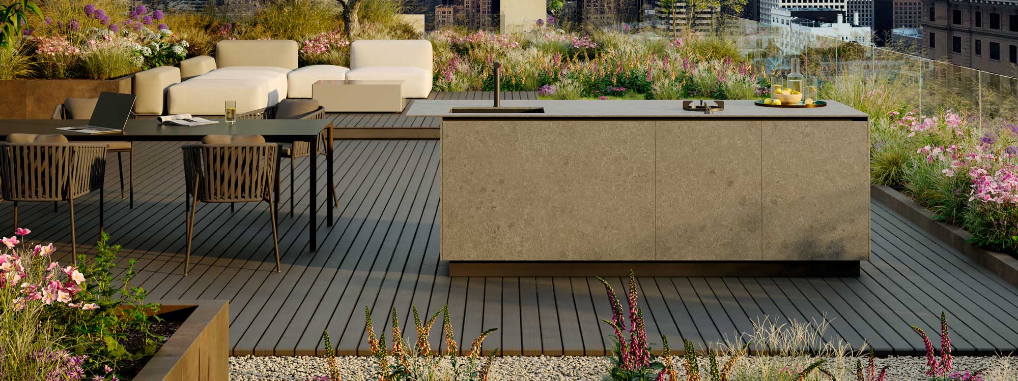 Image of rooftop terrace with OiCook outdoor kitchen island and Twist table and dining chairs, with Elements garden sofa in background, surrounded by flowerbeds