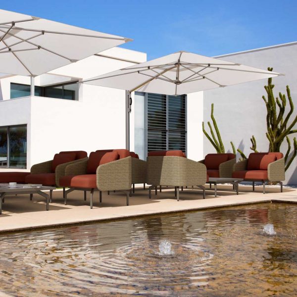 Image of Tuuci Ocean Master cantilever sun shades next to tranquil water feature with whitewashed building and cactus in background