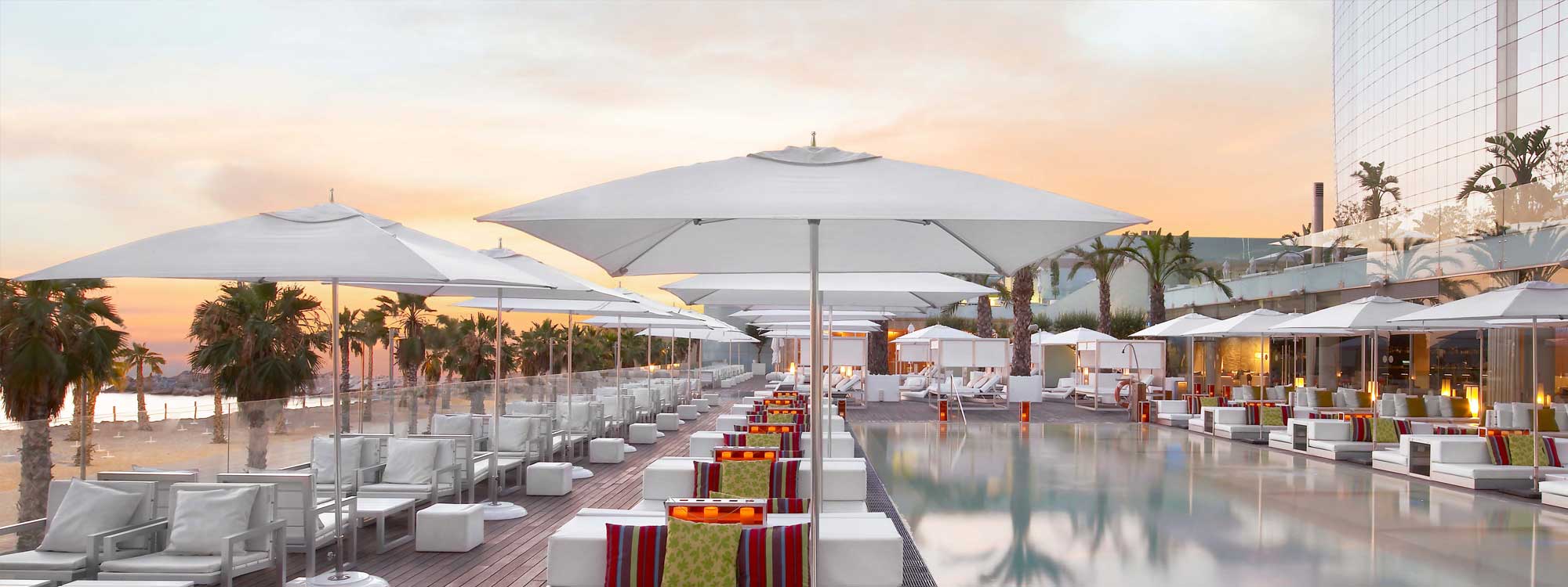 Image of white contract parasols on hotel poolside lounge area