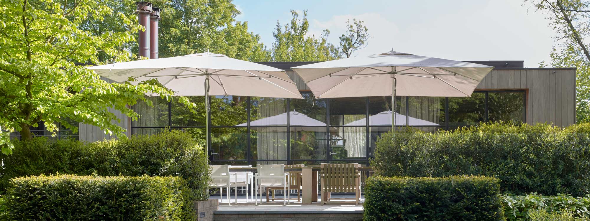 Image of white Tuuci Ocean Master mast parasols with polished titanium mast and ribs on terrace above modern garden furniture