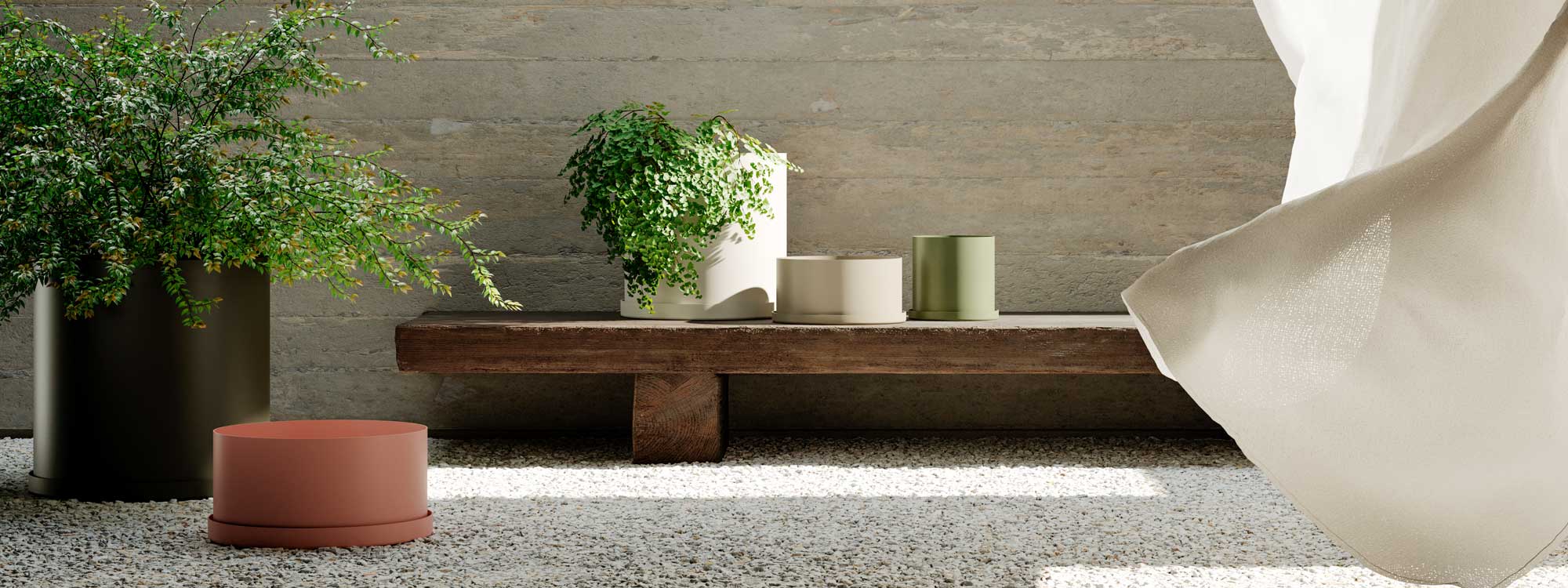 Image of OiSide OiPots minimalist planters in different shapes, sizes and colors, shown on white gravel and wooden bench in the backgroun