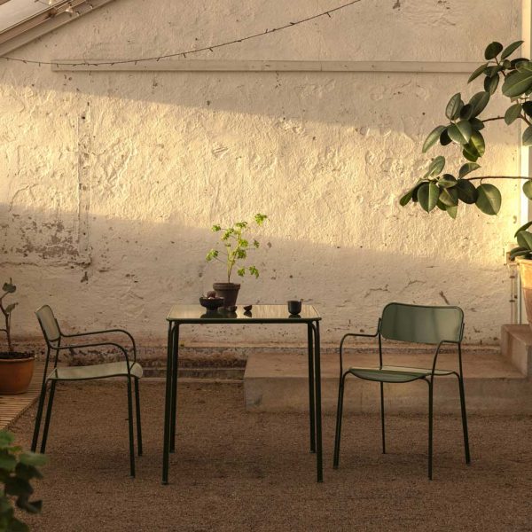 Image of Grythyttan Libelle contemporary garden table and chairs by Grythyttan, shown on gravel terrace in fading late afternoon night