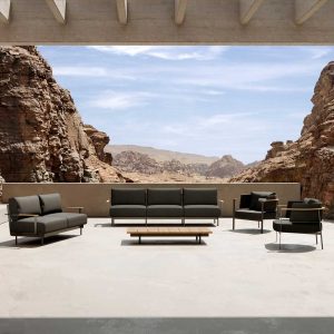 Image of Oiside Penda contemporary garden sofa, low chair and central coffee table on sunny terrace with rocky and arid landscape in the background