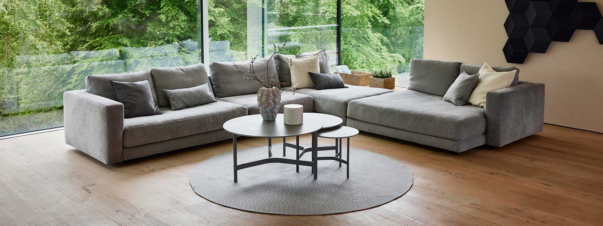 Image of snug Scale corner sofa and daybed with Light grey Cane-line Essence fabric, with nest of Twist coffee tables in the centre