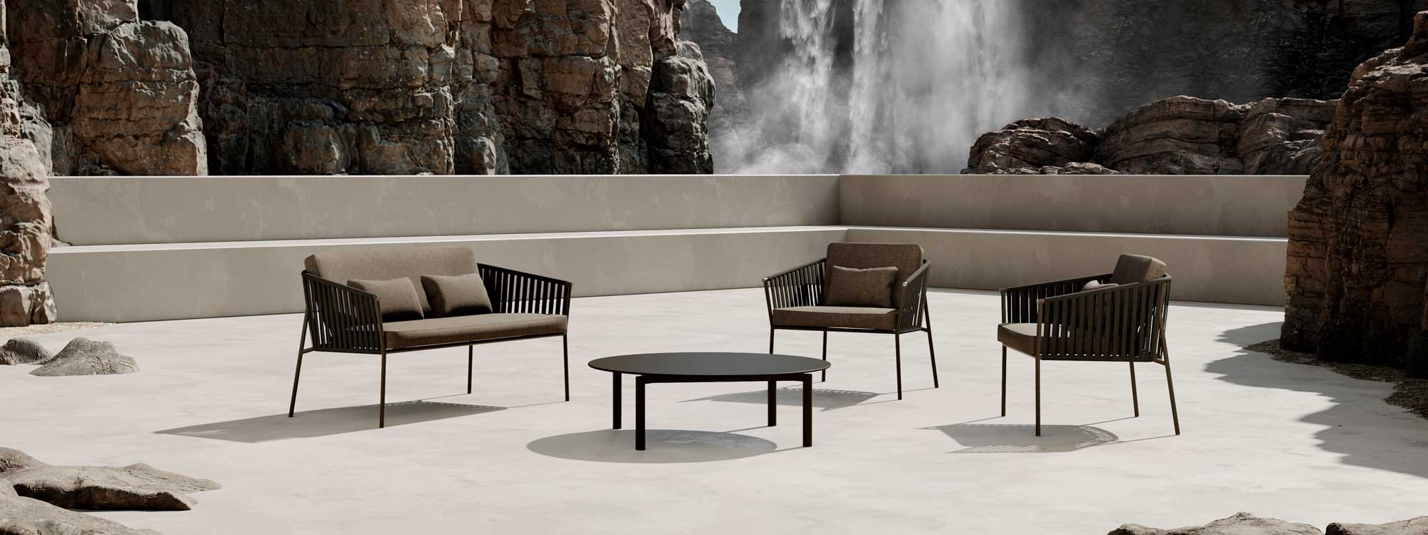 Image of Oiside Twist garden sofa, lounge chairs and low table on a sunny concrete terrace, with rockface and water vapor in the background