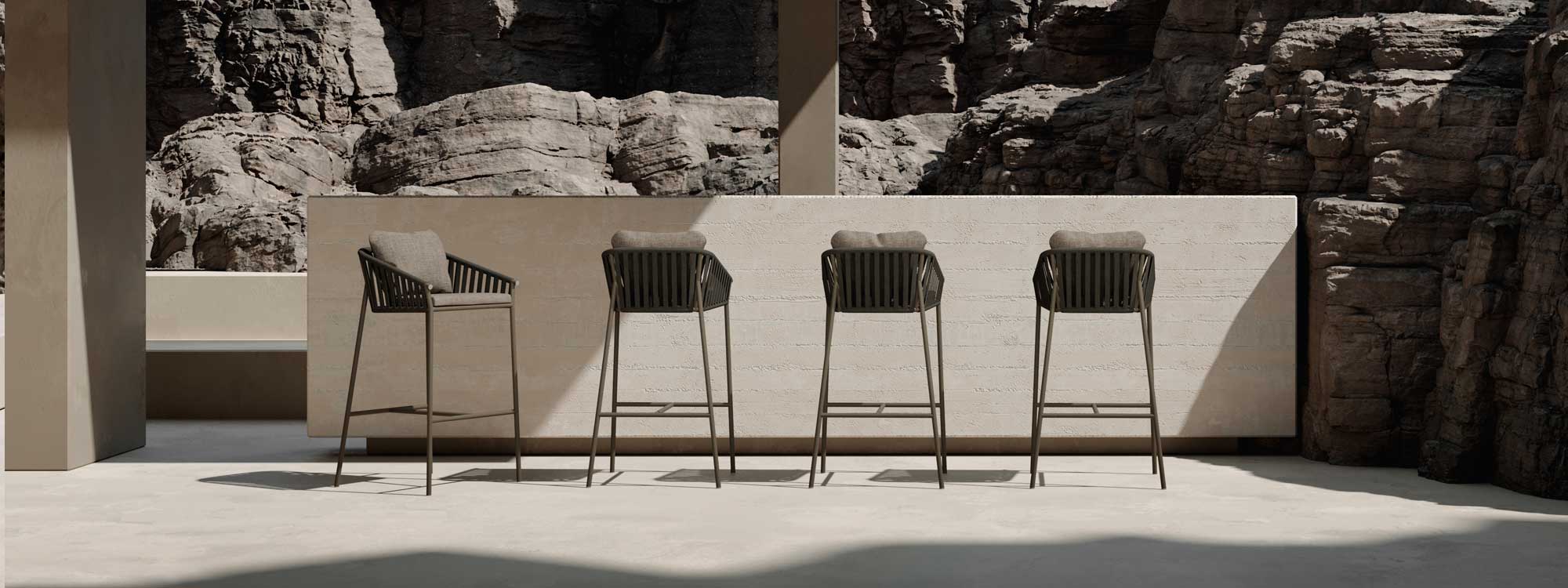 Image of 4 Oiside Twist modern garden bar chairs against bar with raw design, with rockface in the background