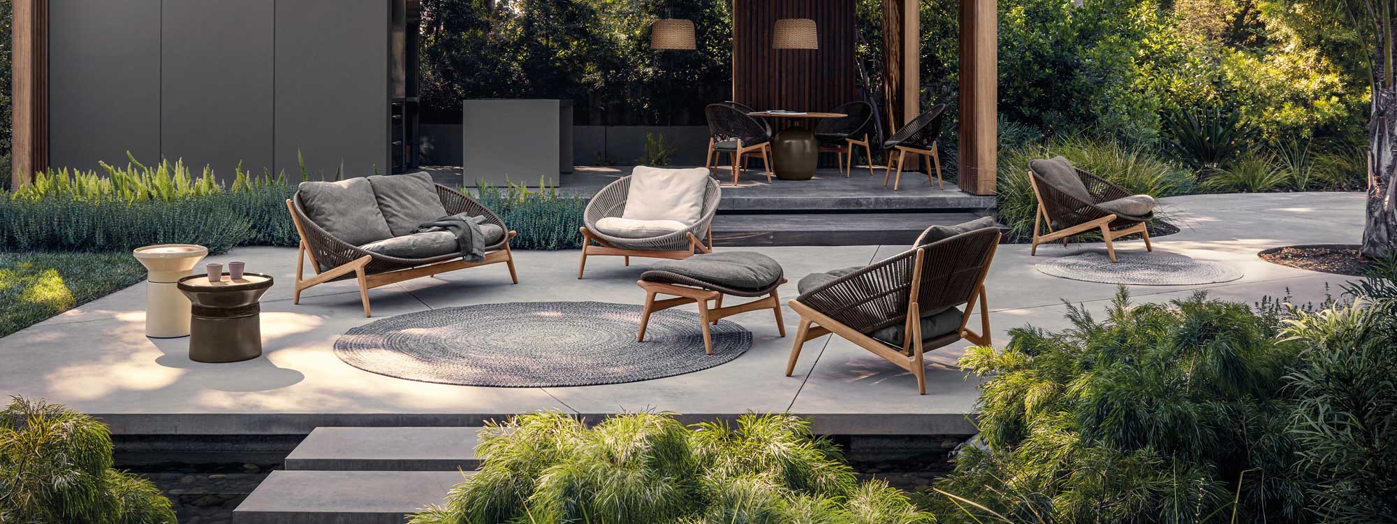 Image of Bora vintage-inspired outdoor lounge furniture on minimalist terrace, with Bora dining chairs and Kasha table by Gloster in the background