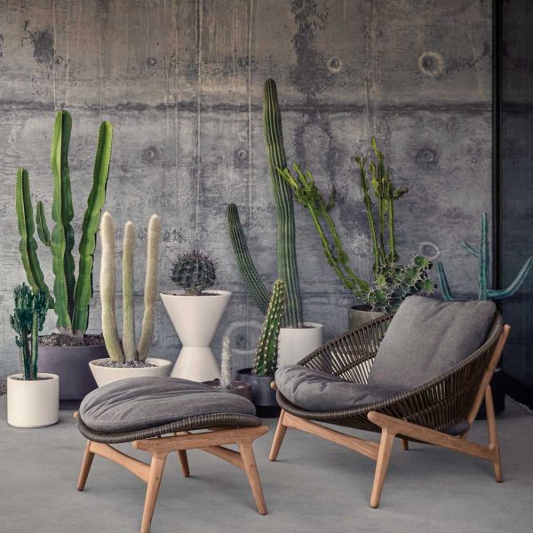 Image of Bora garden relax chair and foot rest by Gloster, with poured concrete wall and cactuses in the background