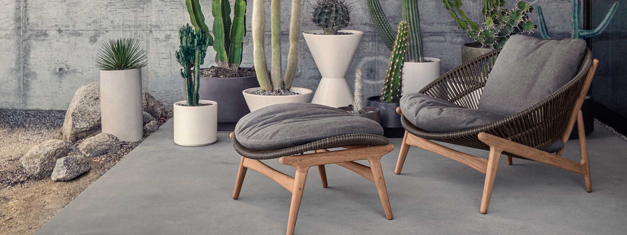 Image of Bora garden lounge chair and foot rest with retro-inspired design by Gloster, with several cactuses in plant pots in the background