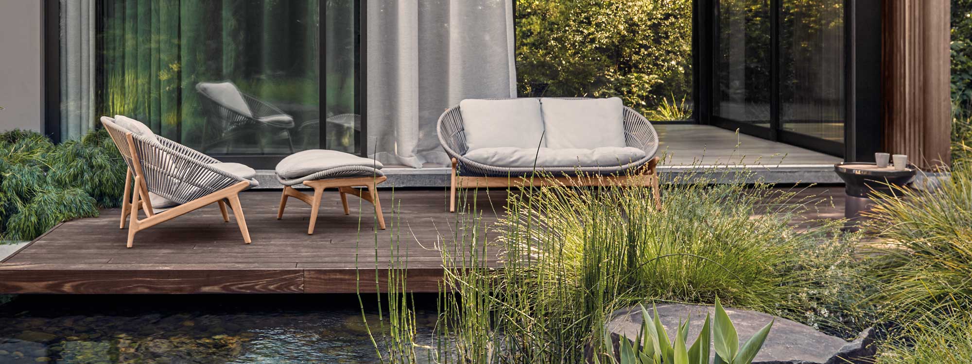 Image of Bora modern teak and rattan lounge furniture and Coso side table by Gloster on wooden decking