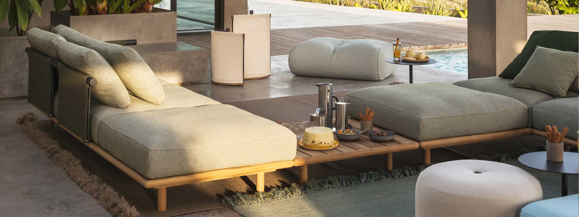 Image in late afternoon of RODA Eden minimalist teak garden sofa, together with Pillow LED lights and Double outdoor poufs