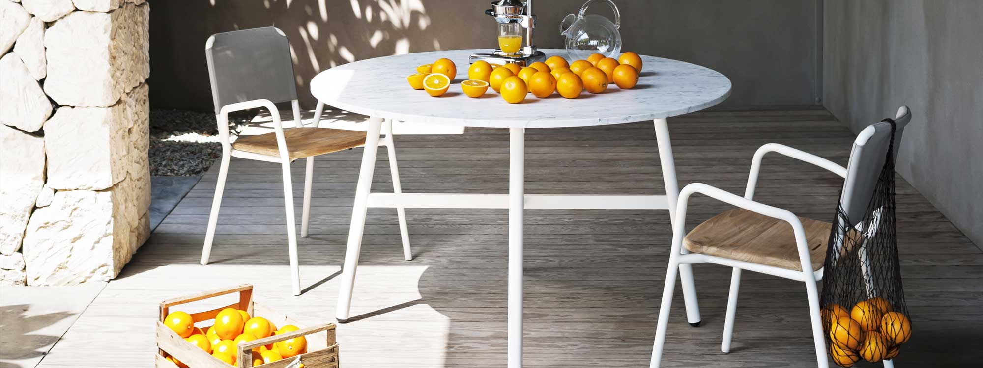 Image of RODA Gamma round garden table with white legs and carrara marble table top, with oranges ready to be pressed on the table top
