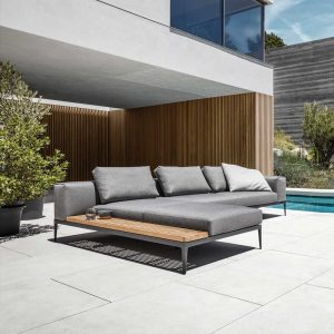 Image of Gloster Grid luxury garden sofa and outdoor chaise on sunny poolside with modern architecture in the background