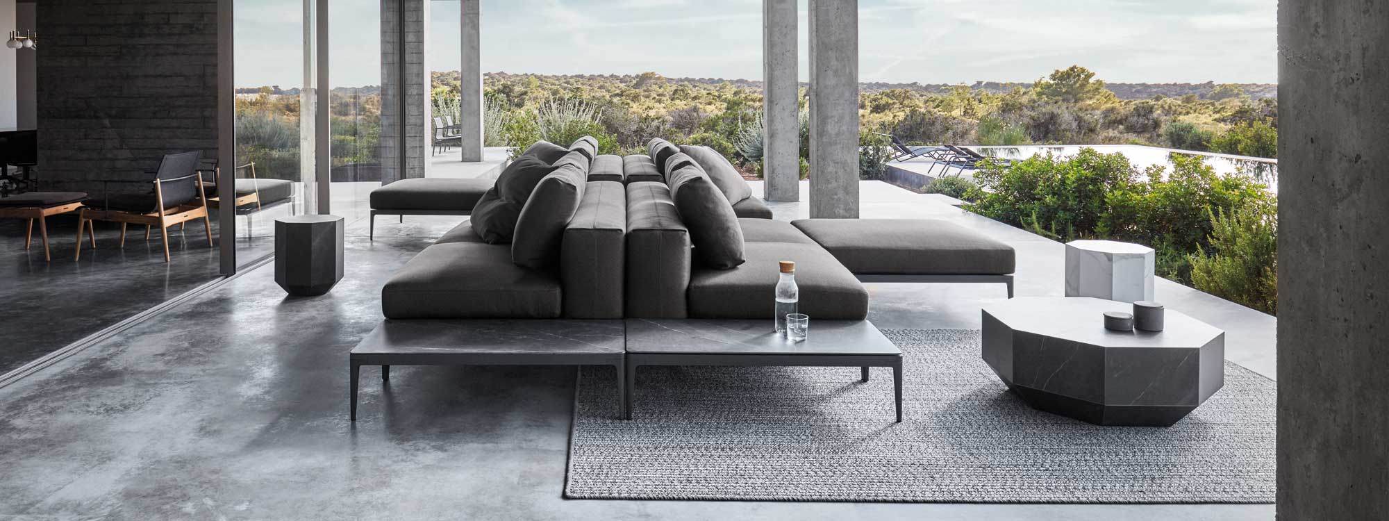 Image of back-to-back Grid luxury garden sofas by Gloster beneath cantilevered ceiling on outdoor terrace