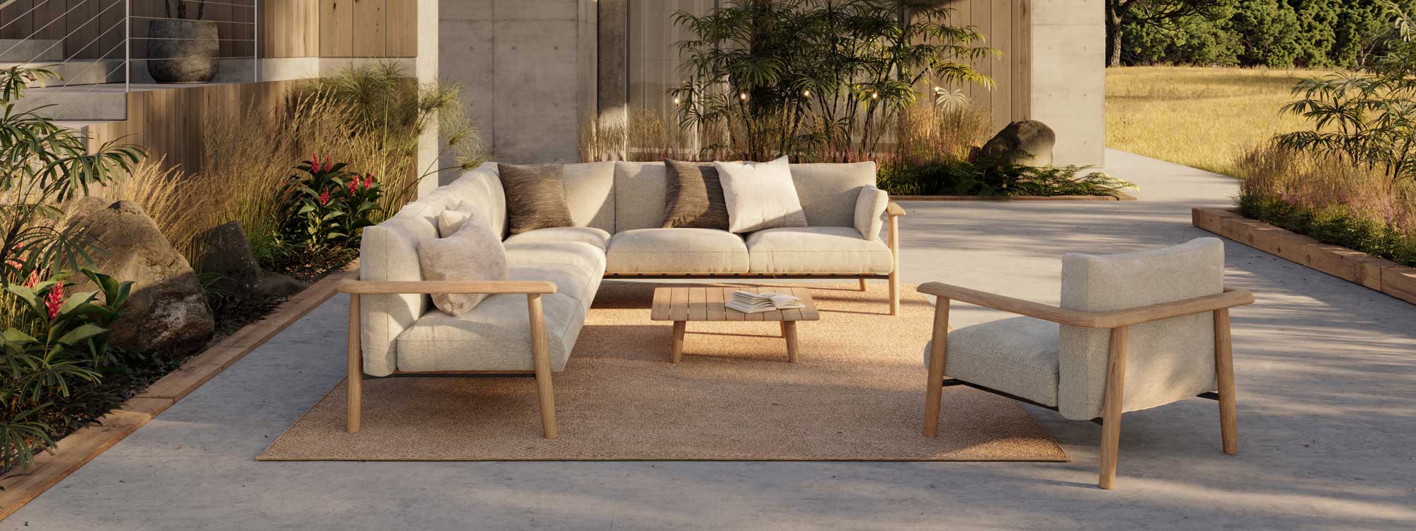 Image of Royal Botania Mambo teak garden sofa on poured concrete terrace, with exotic plants and prairie grassland in the background