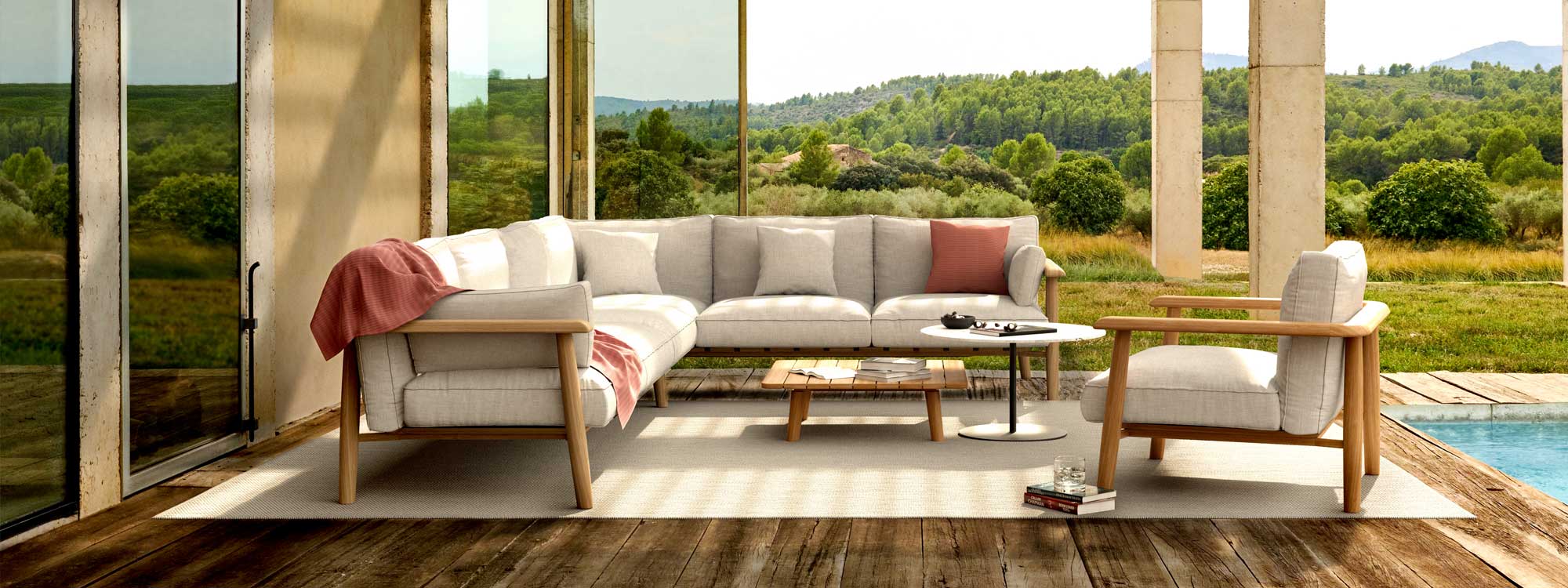 Image of Royal Botania Mambo Lounge teak corner sofa & lounge chair on wooden decking with concrete pillars and wooded hillsides in the background