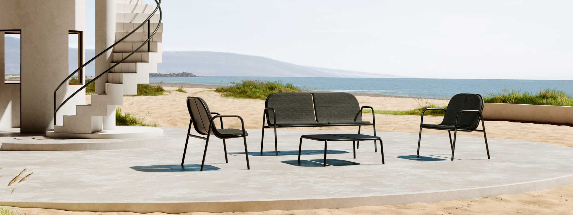 Image of Oiside Parc stacking contemporary outdoor lounge furniture on sunny terrace next to spiral staircase with sand dunes and sea in the background