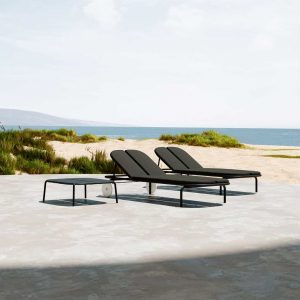 Image of pair of Oiside Parc modern aluminium sunbeds and side table with sea and sand dunes in the background