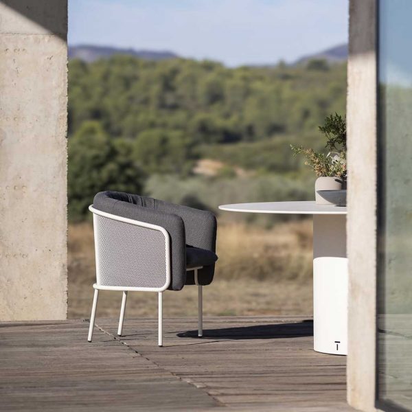 Image of Todus Slide white garden chair with cushions next to Branta modern outdoor table by Todus