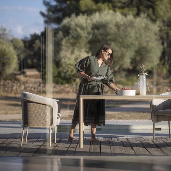 Image of woman setting places at Alca linear garden table next to Slide cushioned garden chairs by Todus