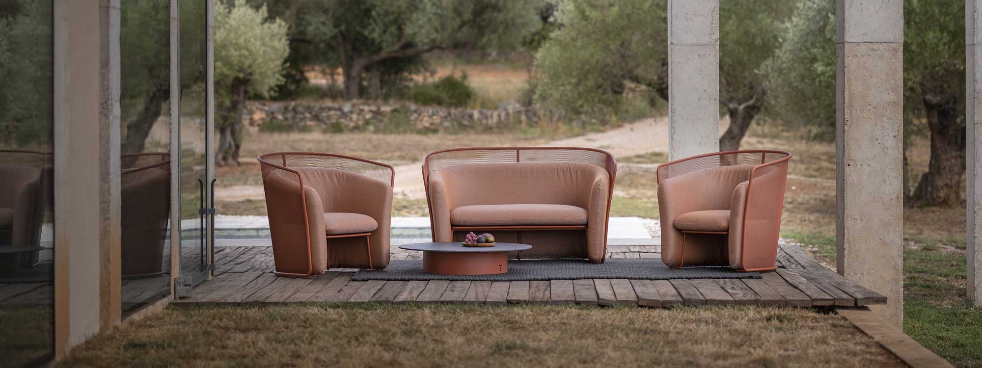 Image of Salmon-Beige coloured Slide modern 2 seat garden sofa, lounge chairs and Branta low table by Todus, on minimalist terrace with olive trees in the background